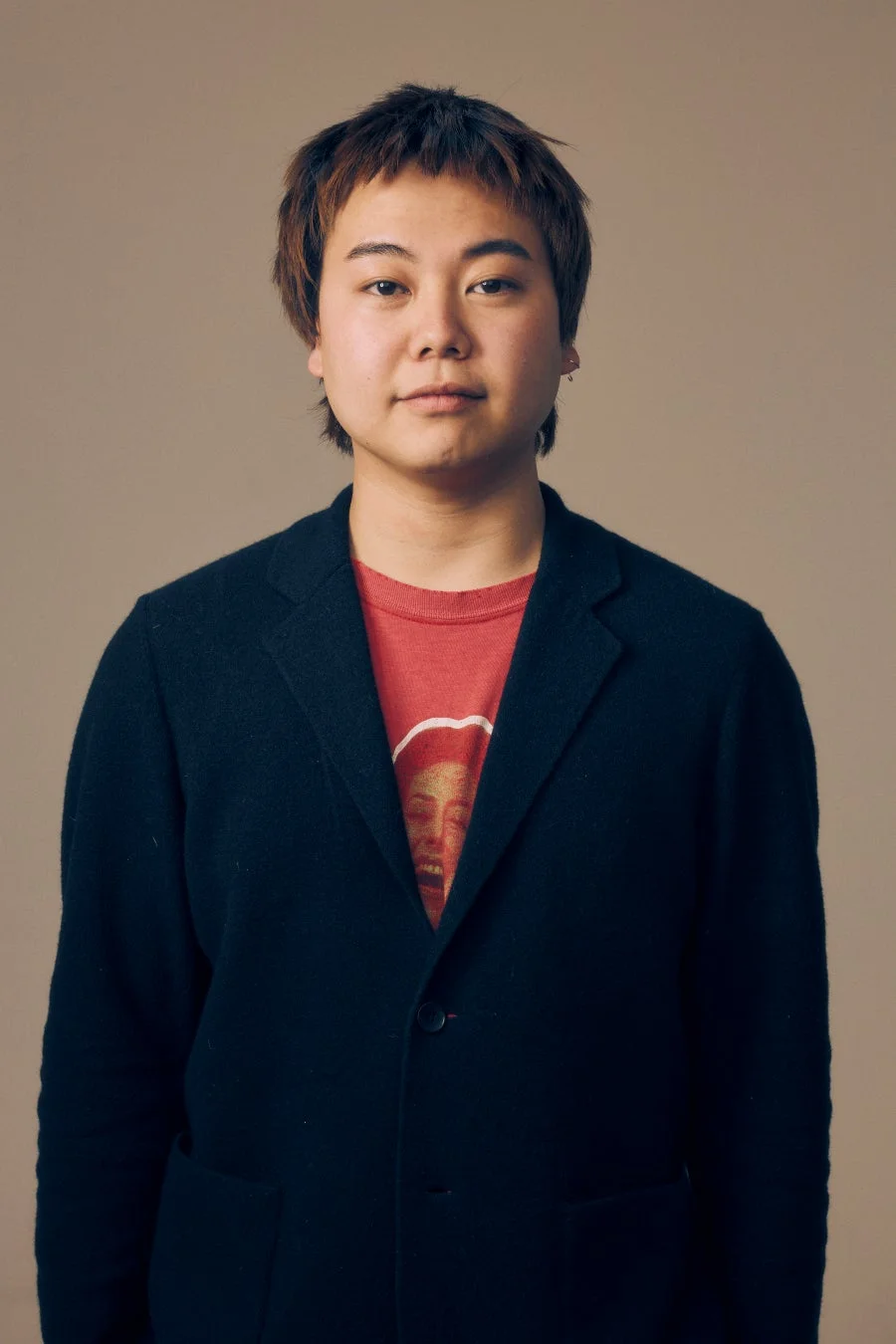 黒いブレザーと赤いTシャツを着た若者