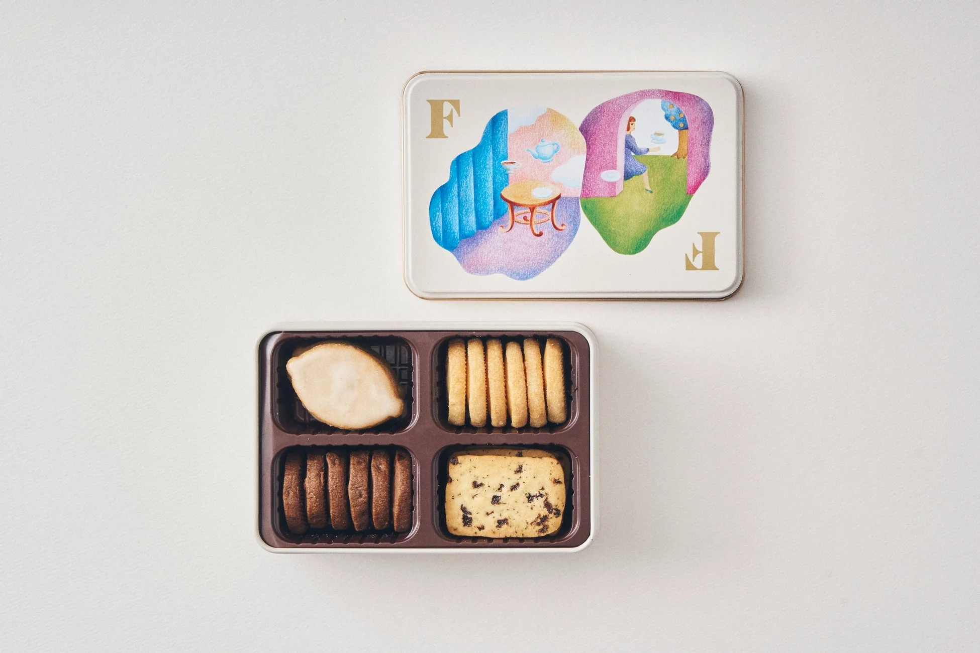 おしゃれなイラストが描かれた蓋の缶と、多種類のクッキーが詰め合わせられたお菓子