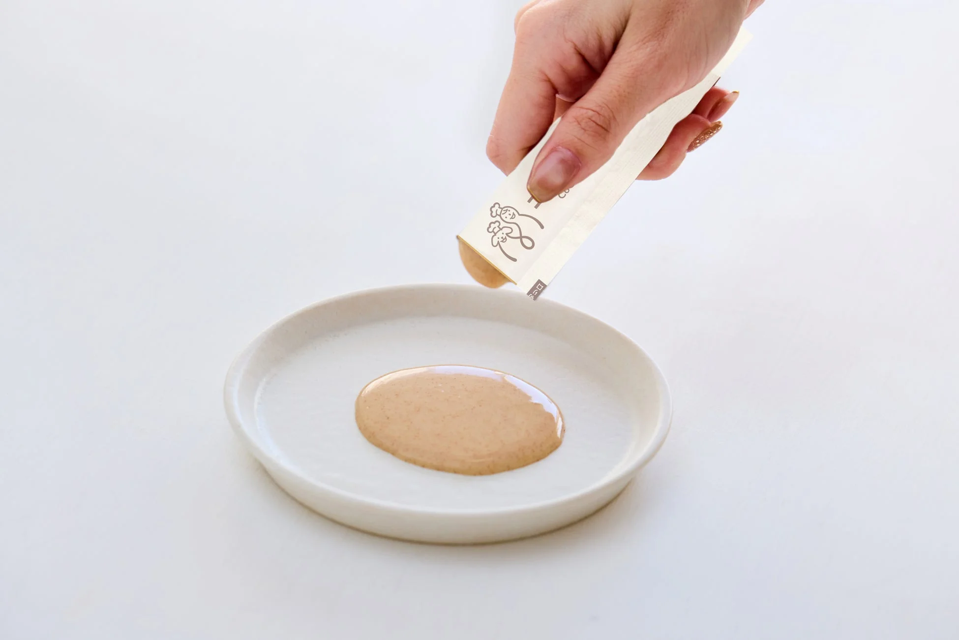 白い皿にソースを絞り出す手