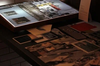 暗がりの空間で、都市風景のコラージュ作品が展示されている様子。