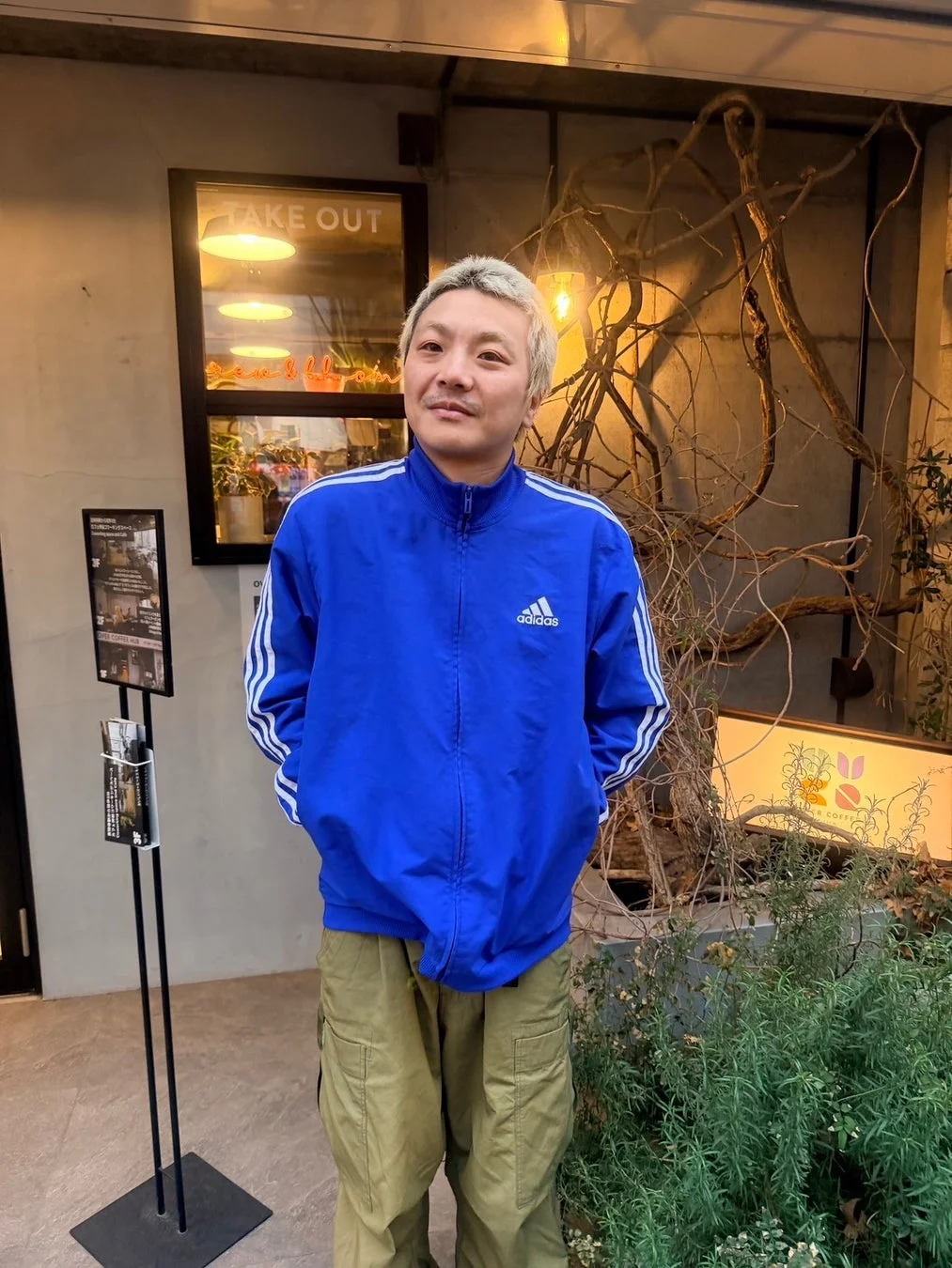 青いアディダスのトラックジャケットを着用した男性