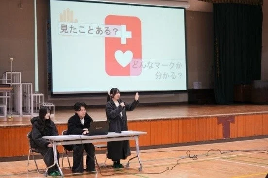 ヘルプマークのプレゼンテーションを行う学生