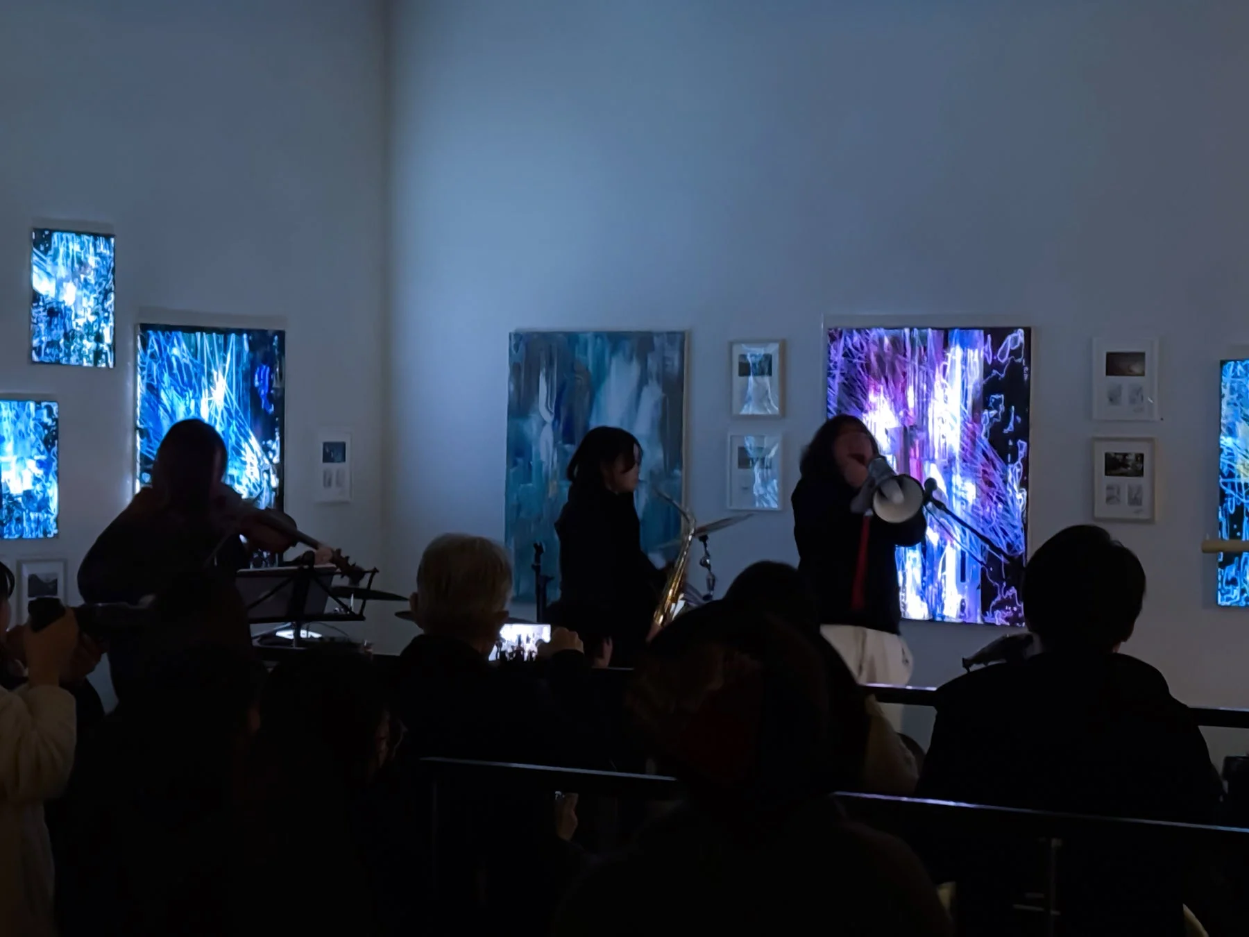 ライブ会場で、ヴァイオリンやサックスを演奏するミュージシャンと観客