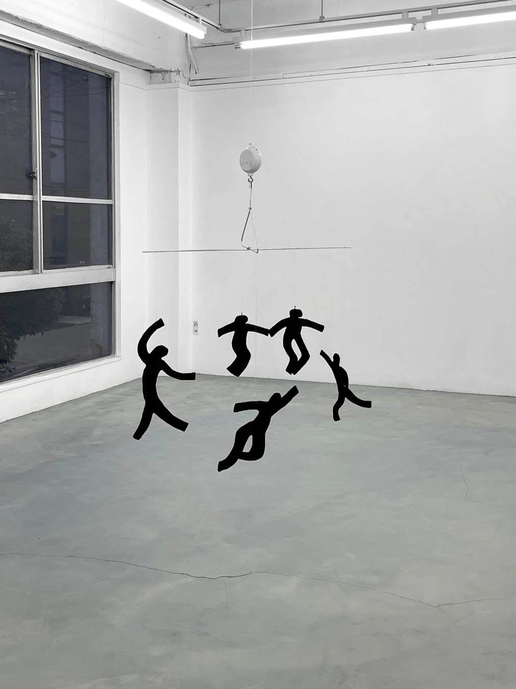 黒い人型のシルエットが吊り下げられたモバイルアートが展示されたギャラリー空間