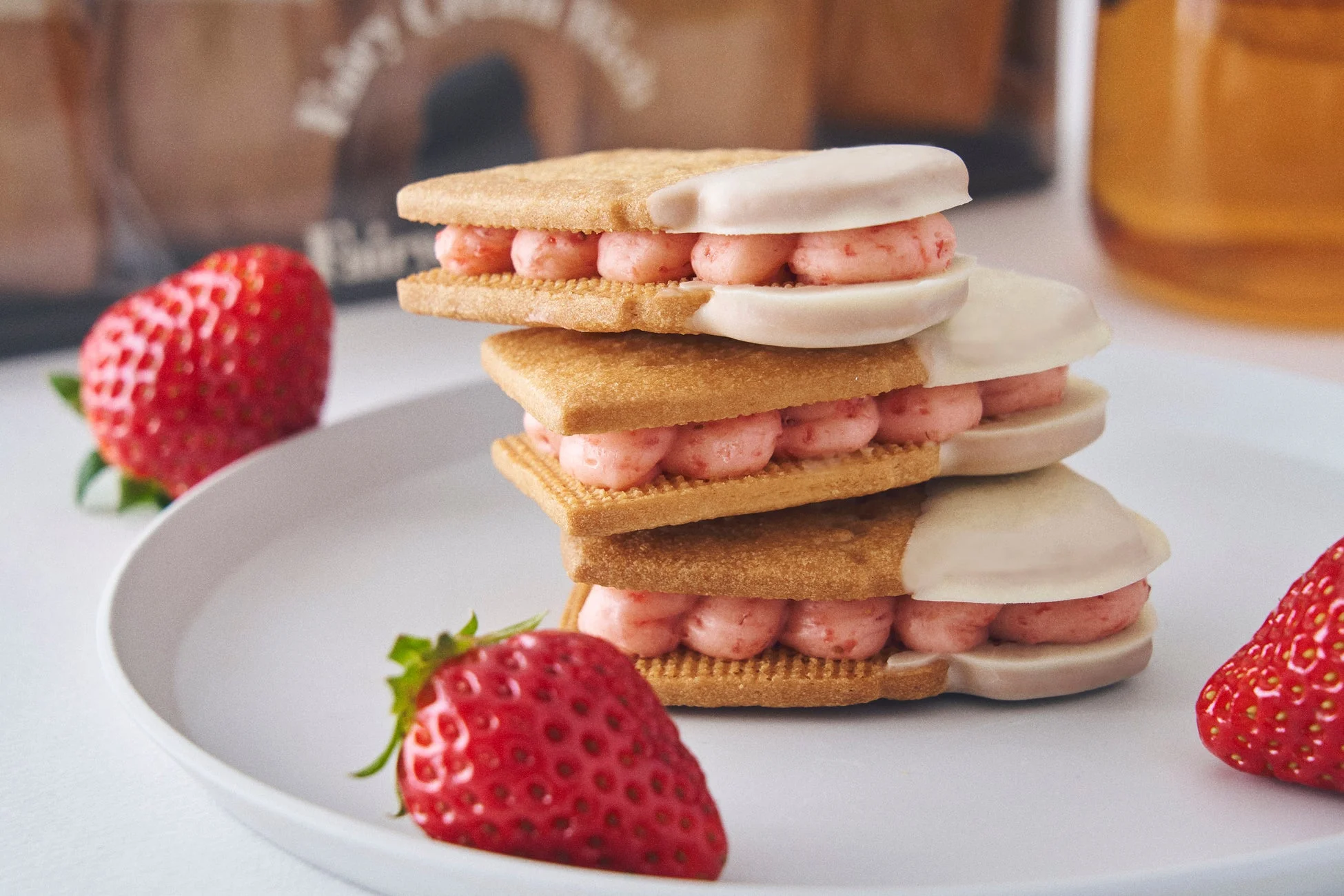 白いお皿に積み重ねられたいちごクリームサンドクッキーと新鮮ないちご