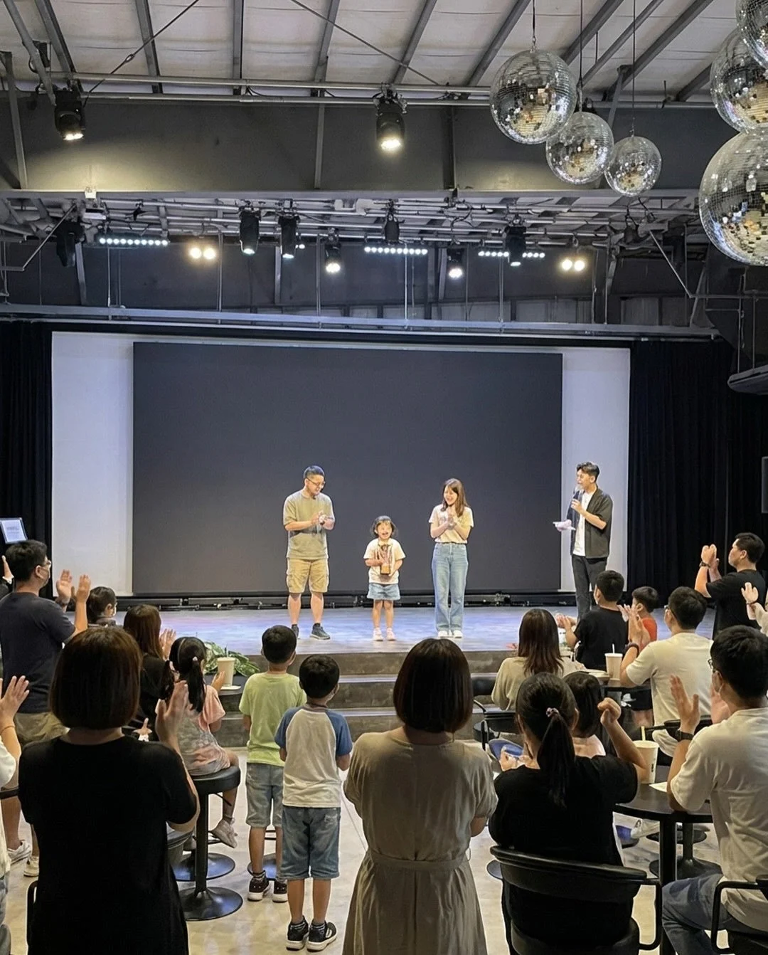 ステージで拍手する観客と出演者