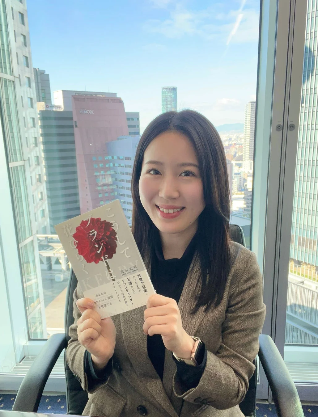 書籍「こうして、ブランドは花ひらく」を持つ女性
