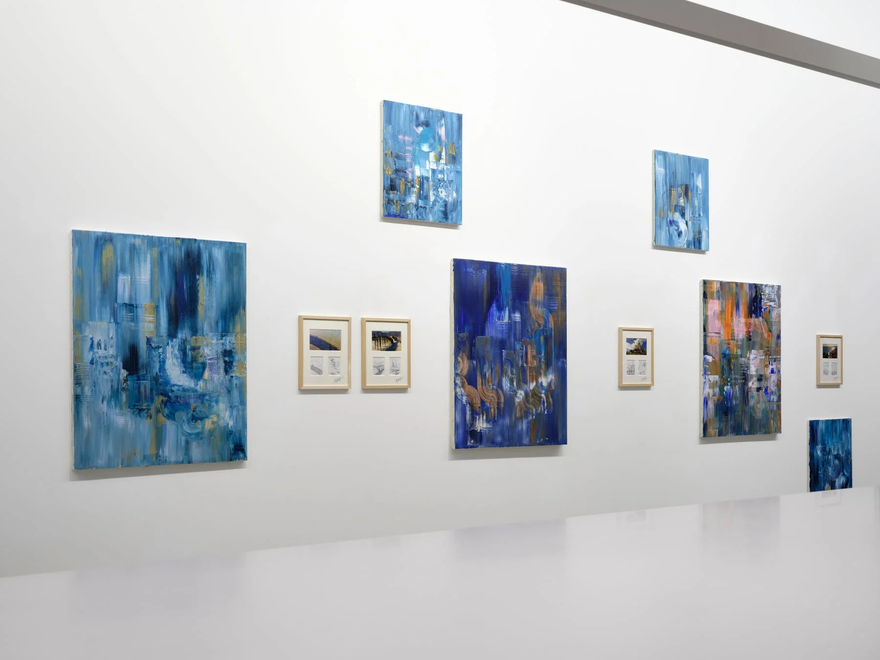 白い壁に複数の抽象画が展示されている現代アートギャラリー