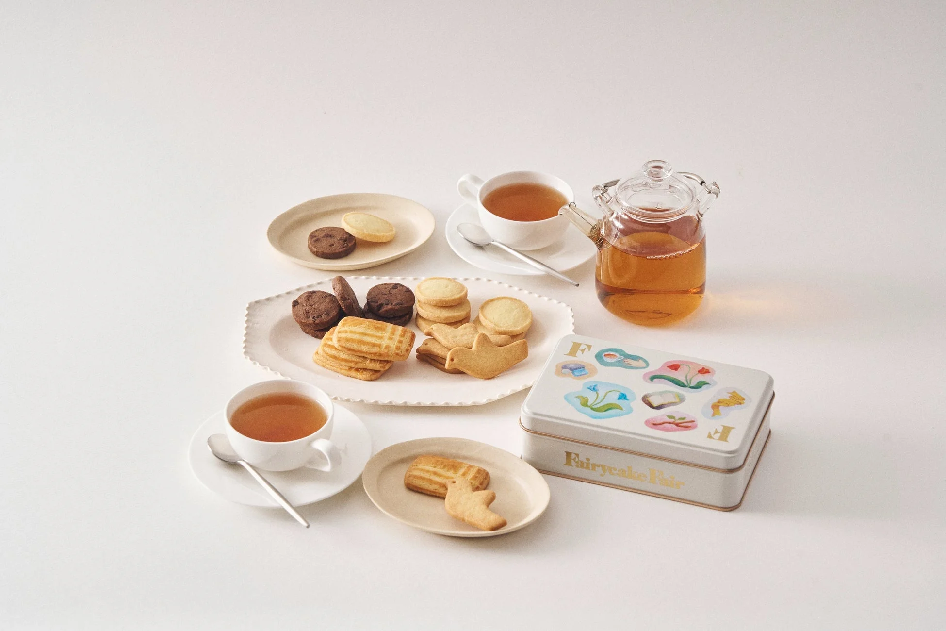 数種類のクッキーが盛り付けられたお皿と、ティーカップに入った紅茶、そしてティーポット
