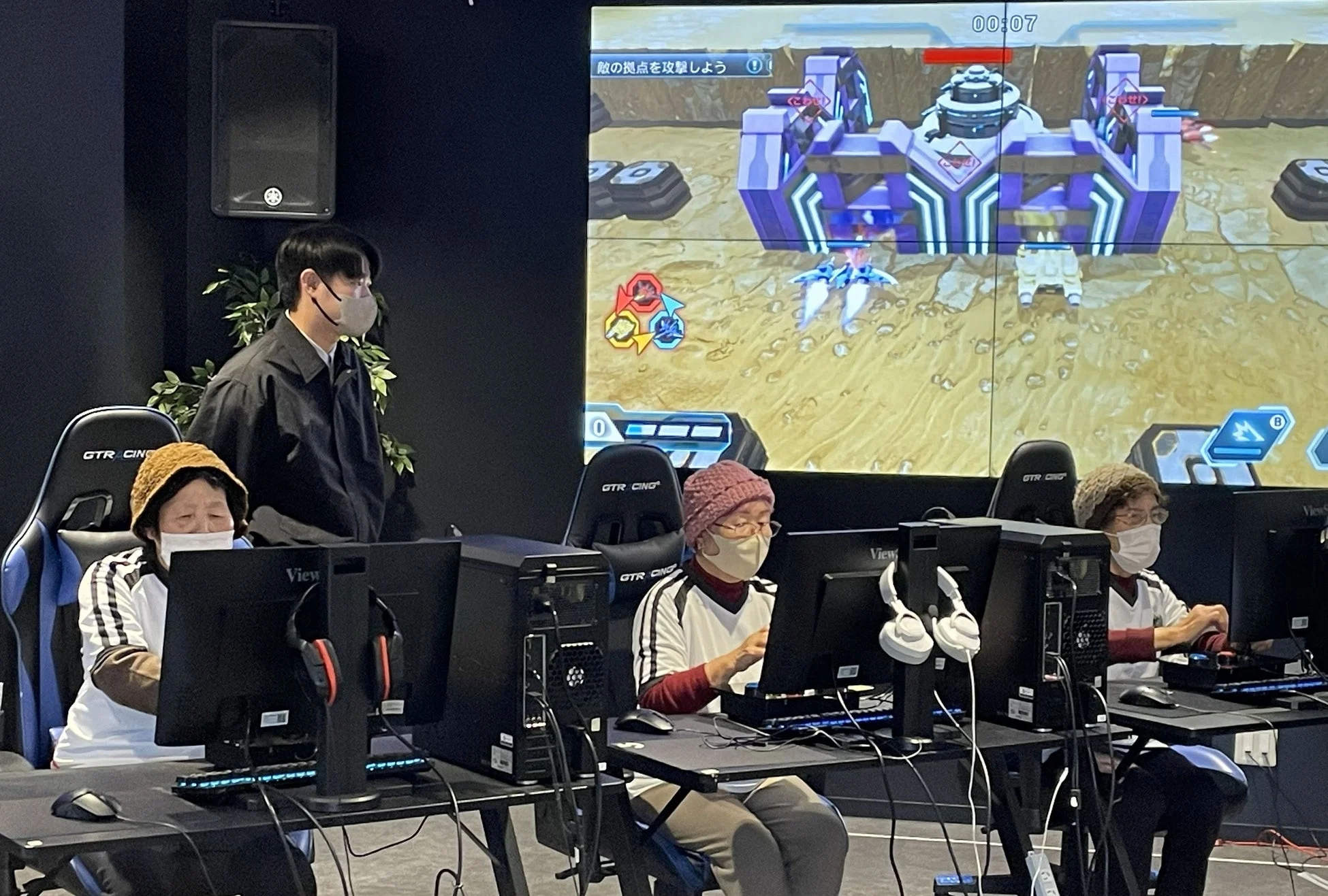 高齢者たちがPCモニターに向かい、eスポーツゲームを楽しんでいる様子
