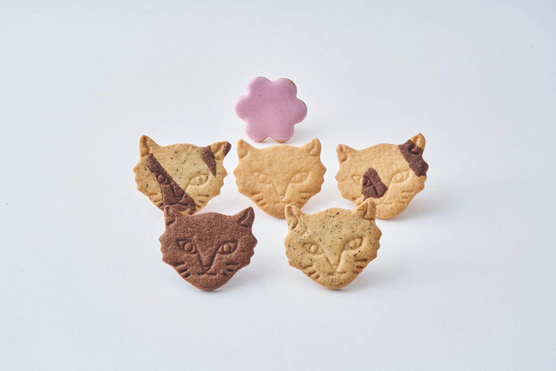 猫の顔の形をしたクッキーと、ピンク色の花形のクッキー