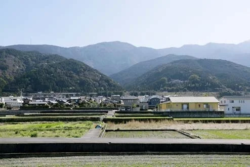 山々を背景に、田畑や住宅、橋が広がる日本の田園風景