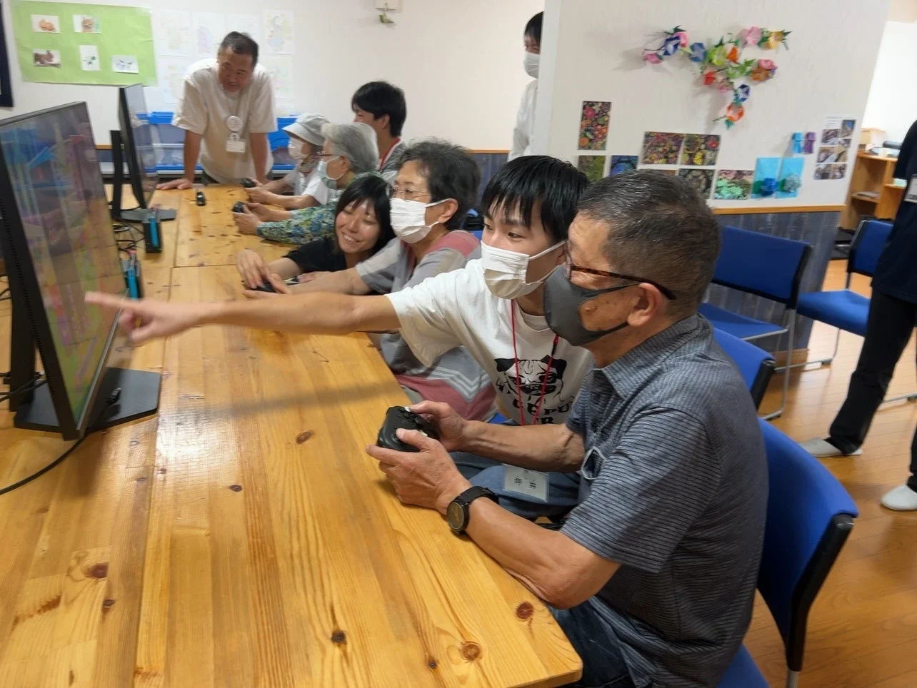 高齢者と若者が一緒にビデオゲームを楽しむ様子