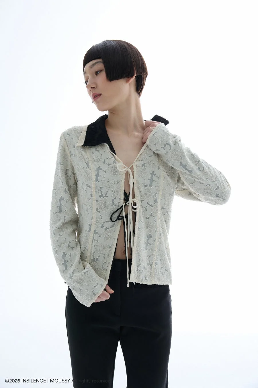 テクスチャーのある白いトップスと黒パンツのモダンな装い