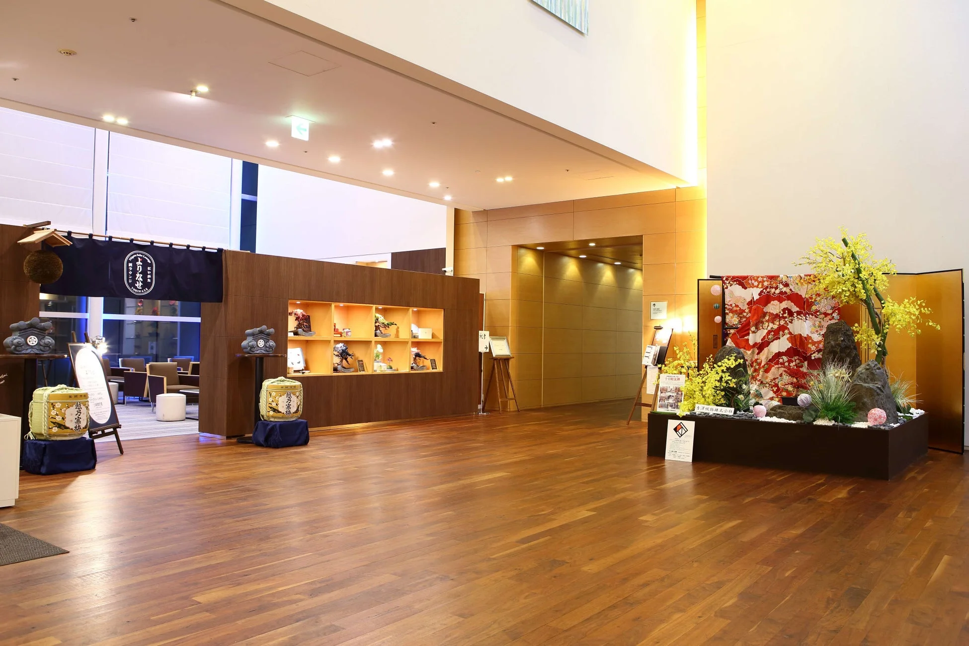 ホテルのロビーらしき空間に飾られた日本酒の樽や盆栽、生け花