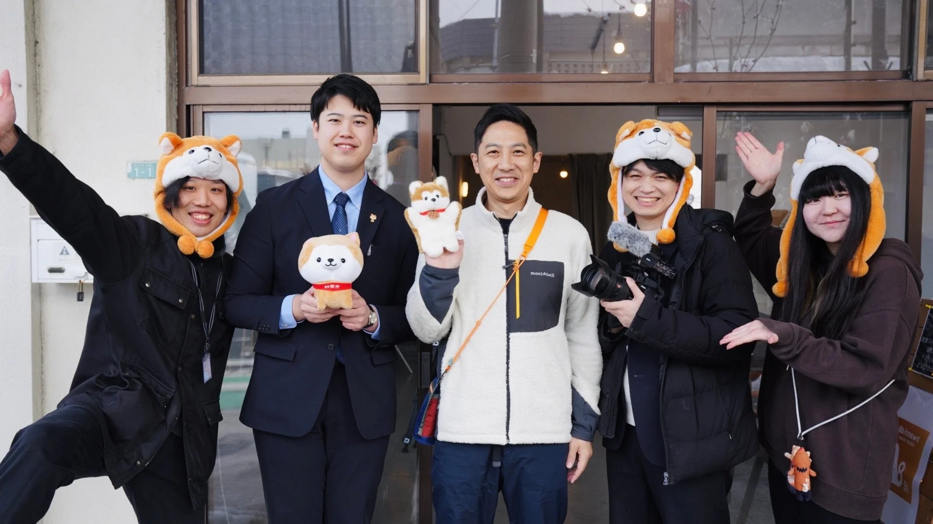 犬の帽子をかぶったり、ぬいぐるみを抱いたりした5人の男女の集合写真