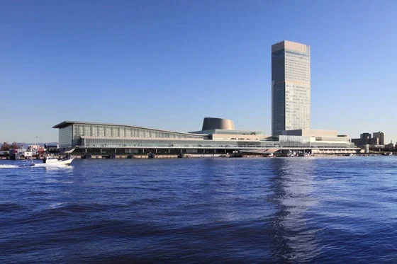 晴れた青空のもと、水辺に建つ近代的な建築群