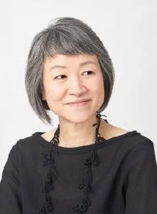 笑顔でカメラを見つめる、短く白い髪のミドルエイジの女性