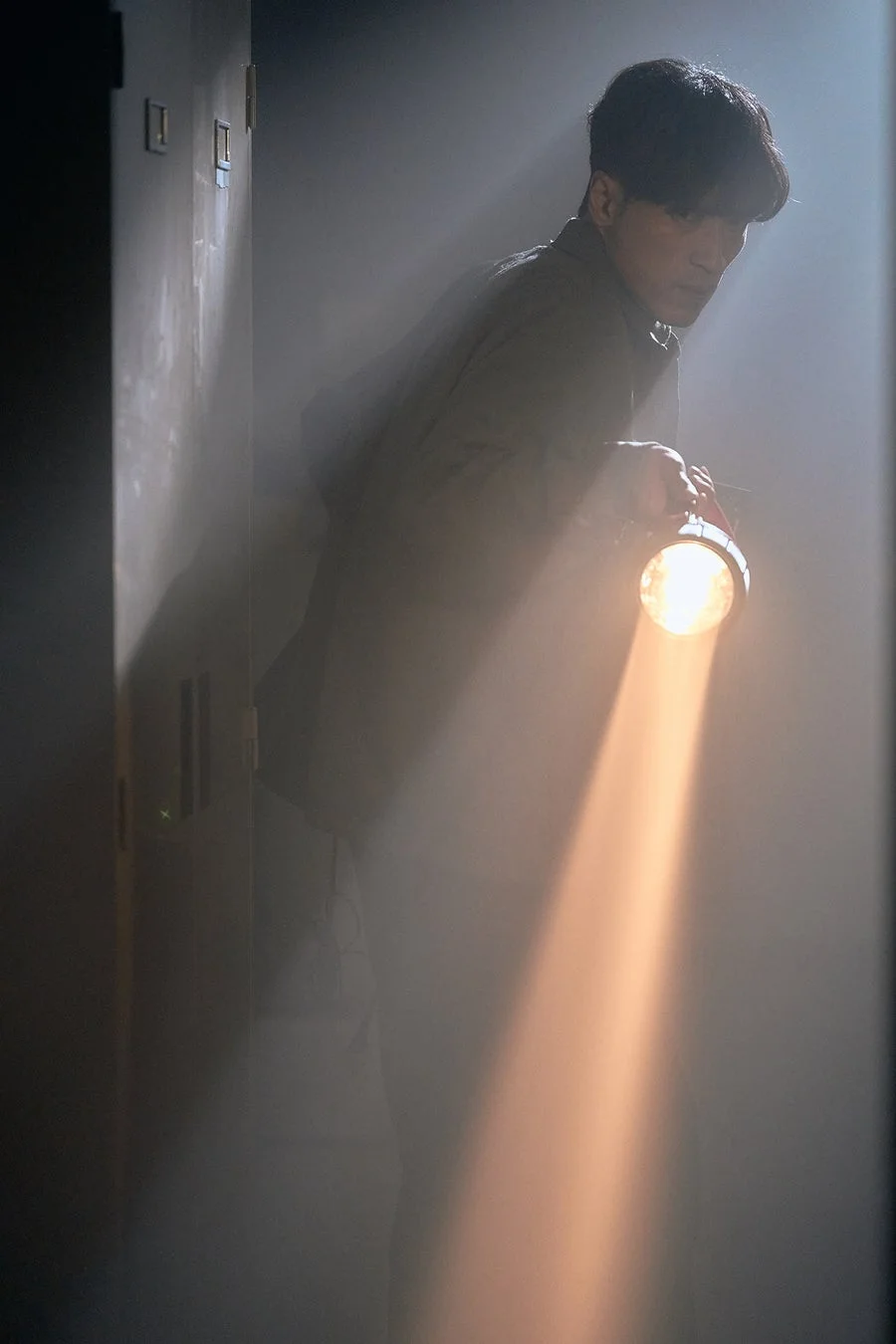 懐中電灯を持つ男性がロッカーを探索する場面