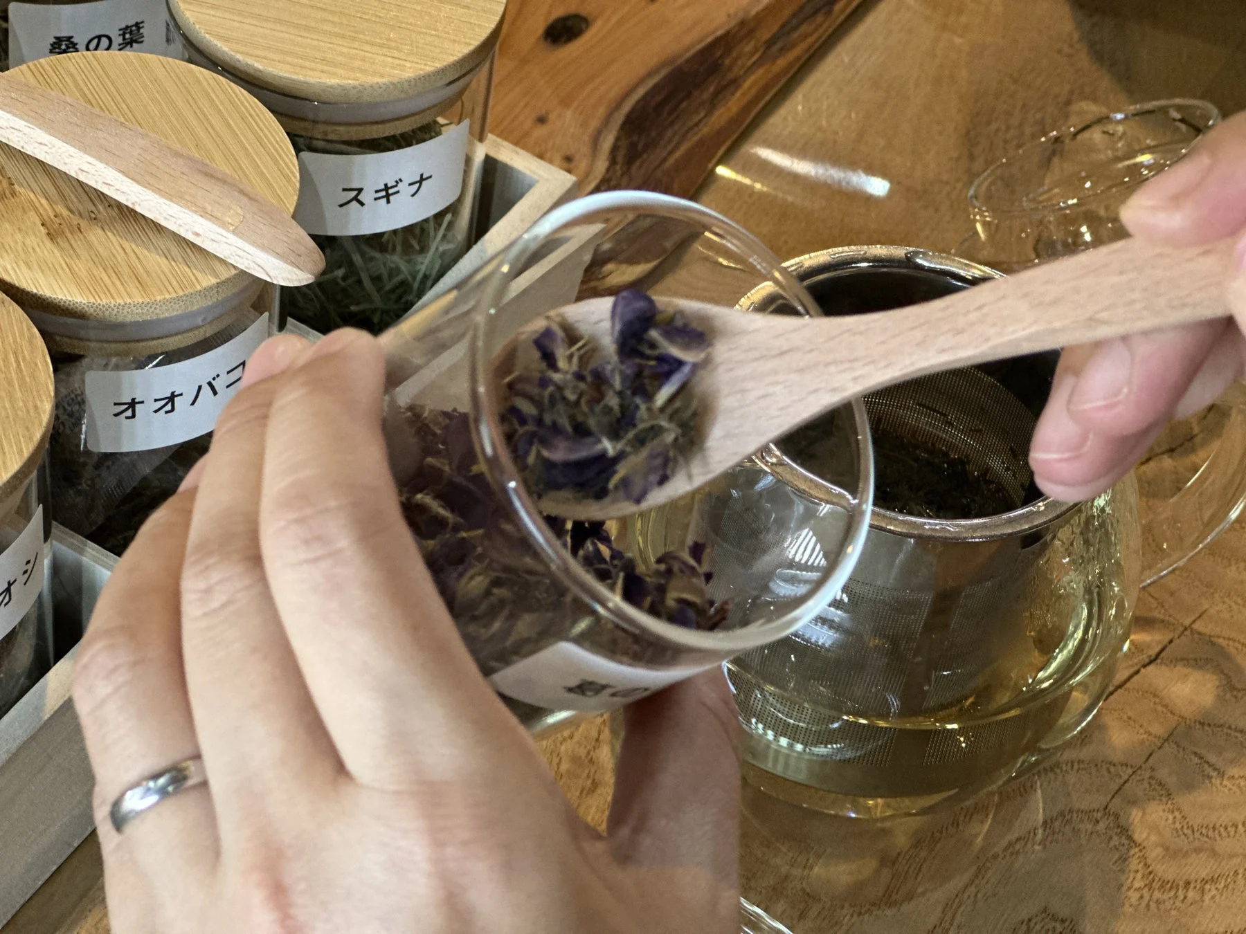 ガラス瓶に入ったハーブをティーポットに移す様子