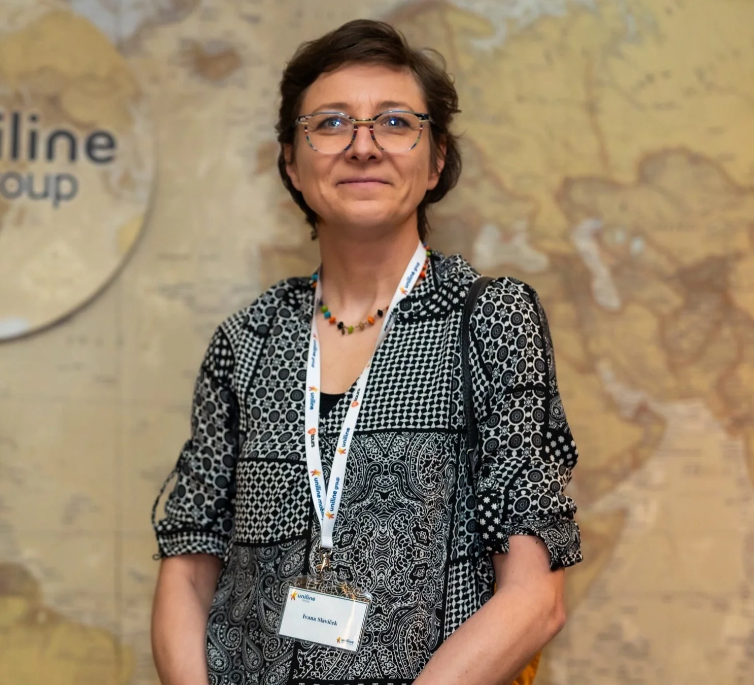 眼鏡をかけた女性が微笑んでいるポートレート、uniline groupのロゴが見える