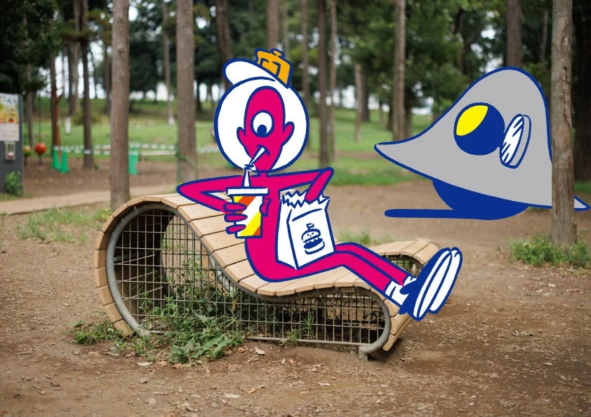 公園のベンチで、ピンク色のキャラクターが飲み物とハンバーガーの袋を持ってくつろいでいる。その傍らには、別のグレーのキャラクターが浮遊している。