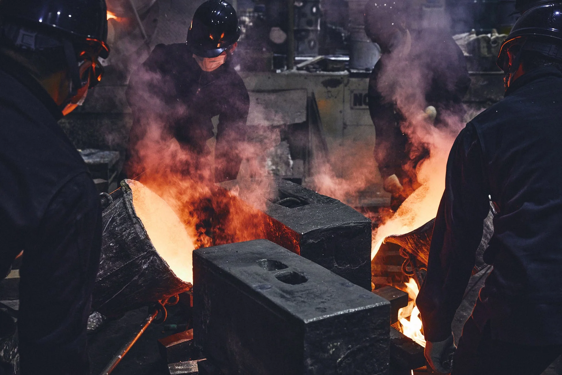 鋳造所で溶融金属を鋳型に注ぎ込む作業員たち