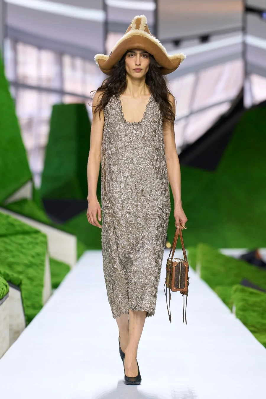 きらびやかなドレスとファーの帽子、ルイ・ヴィトンのバッグを持つモデル