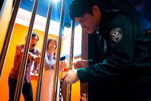 脱出ゲームの牢屋に入れられた男女と警察官