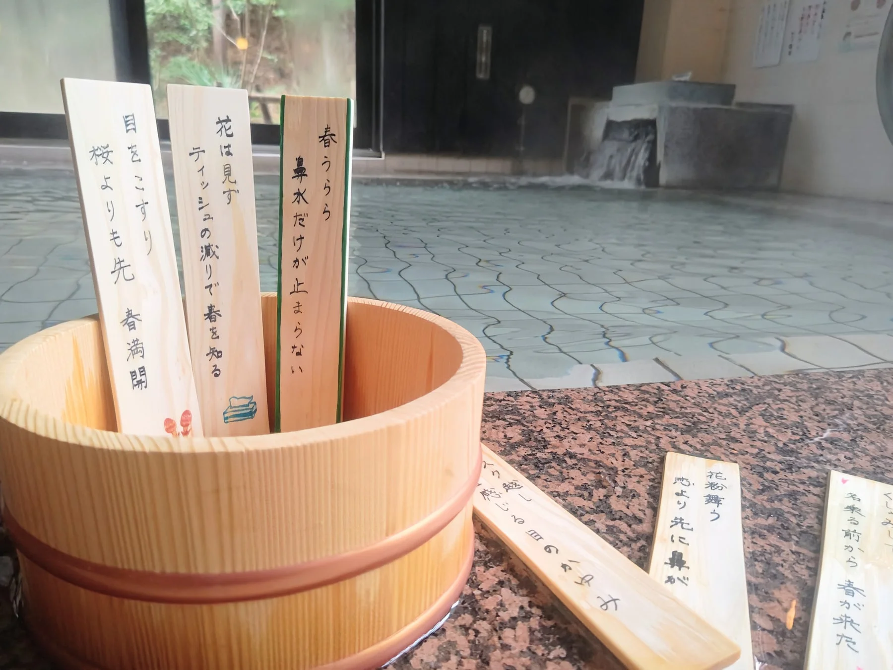 花粉症川柳が書かれた木札が浮かぶ露天風呂
