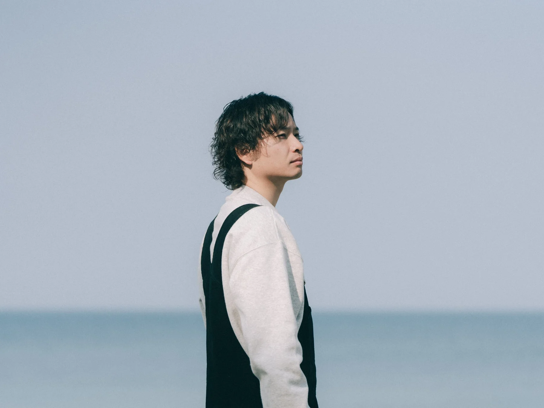 海を背景に横顔を見せるビデオグラファー とみ/Tomiさん