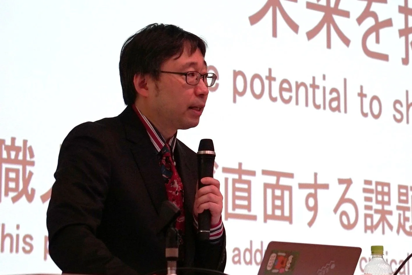 平野大准教授がマイクを手に話す様子