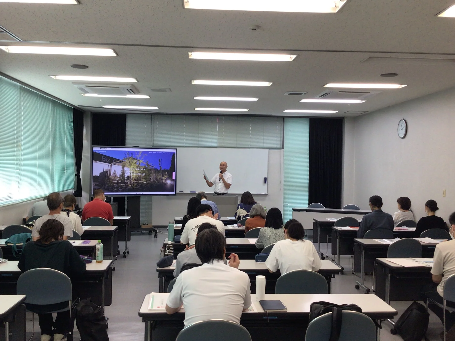 プロジェクターを背景に受講者に向けて話す講師