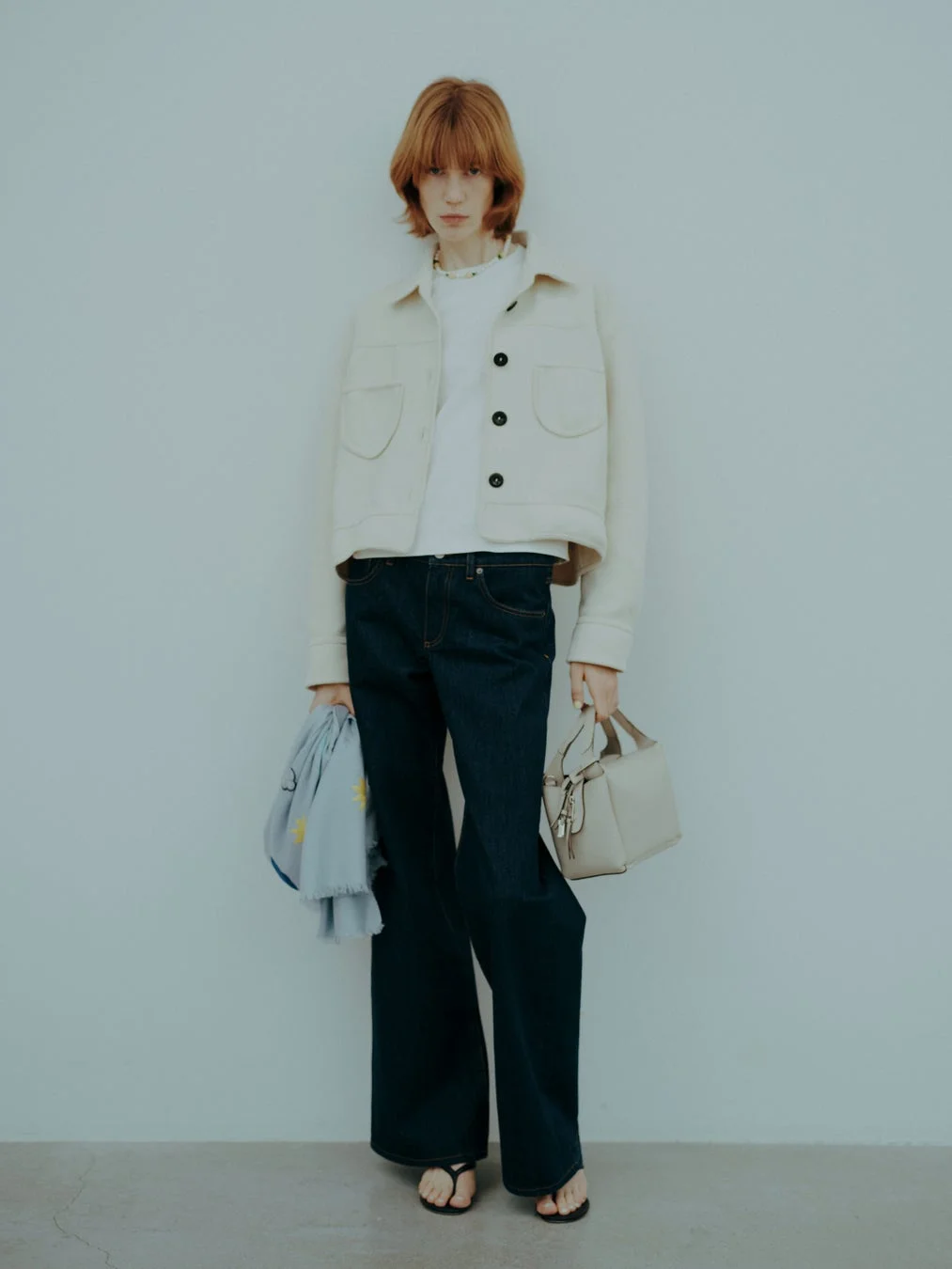 クリーム色のショートジャケットとワイドデニムを着用したモデルの全身写真
