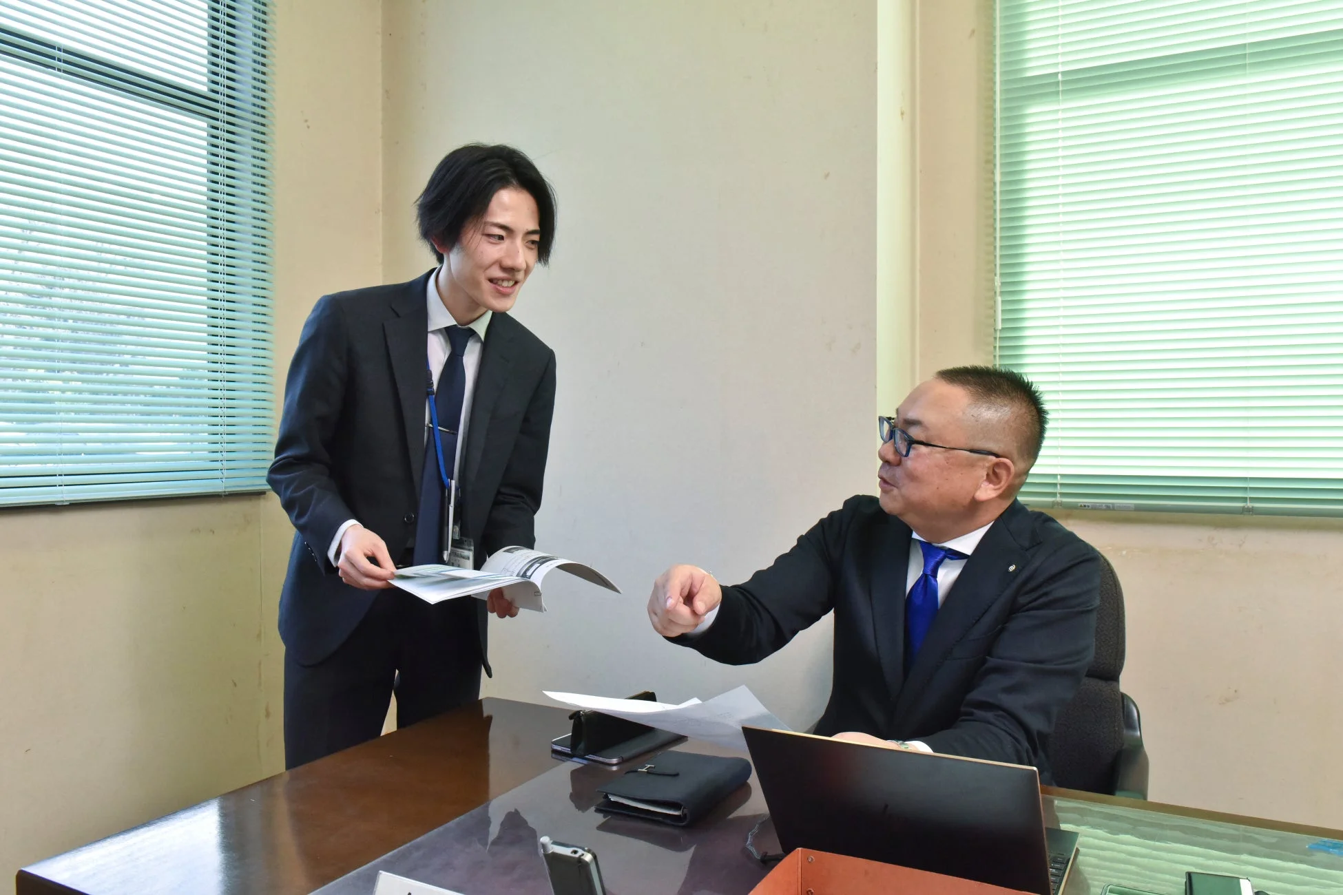 書類を囲んで打ち合わせをする二人のビジネスマン