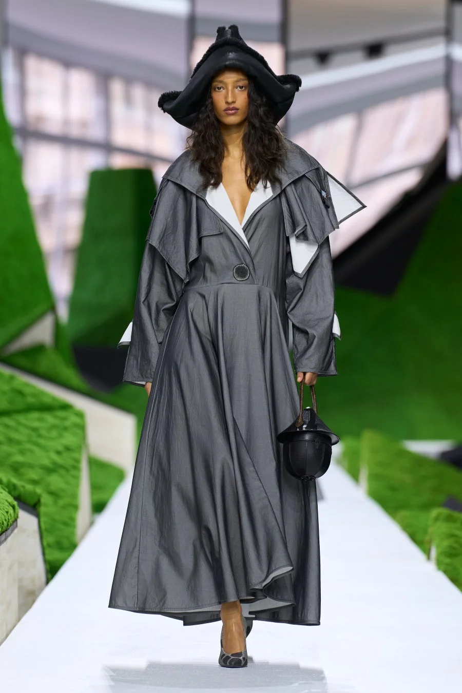 特徴的な黒い帽子とグレーのロングドレスを着用したモデル