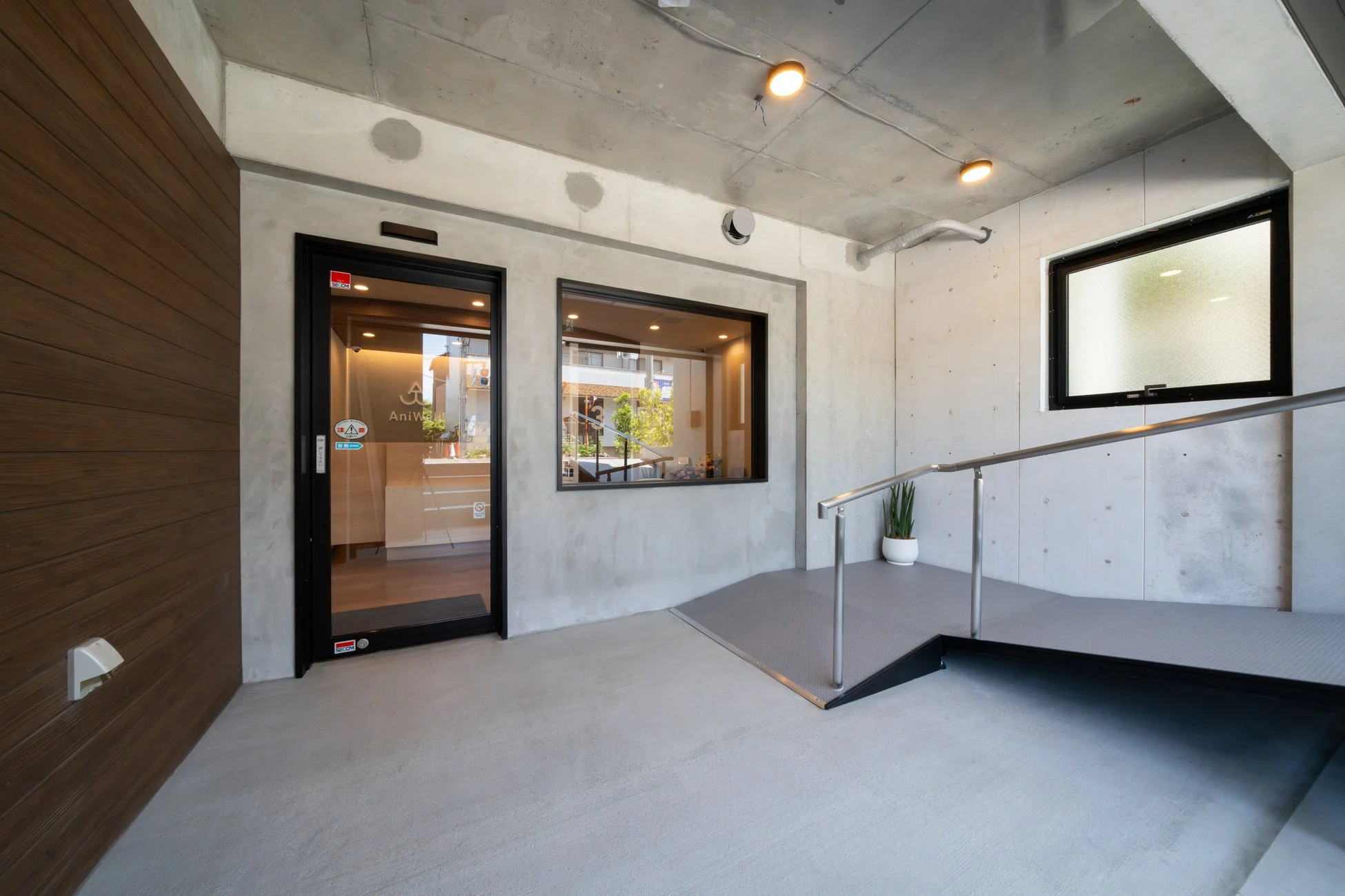 車椅子用のスロープが設置されたモダンなデザインの建物のエントランス