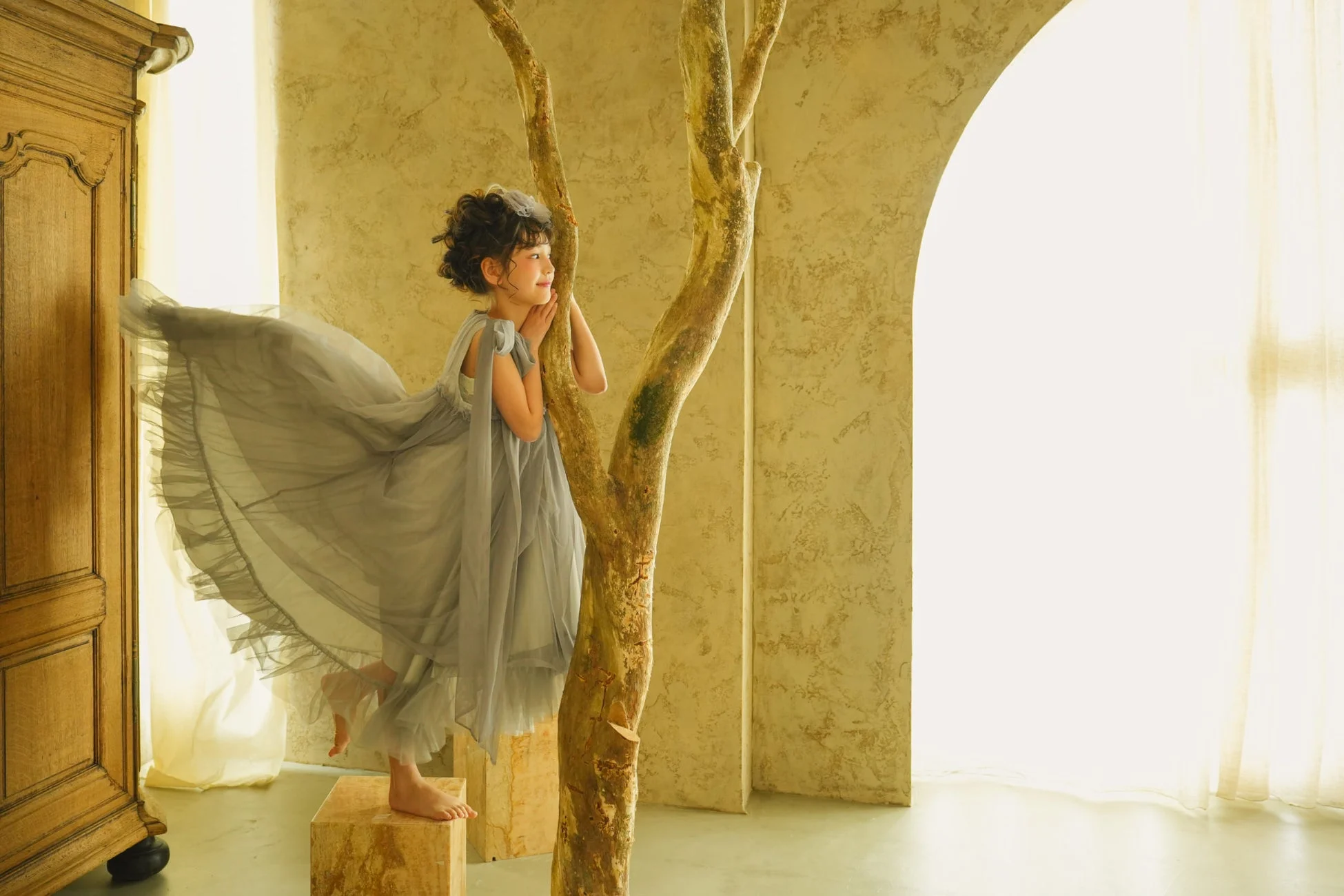 木のオブジェに寄り添い微笑む子供のポートレート