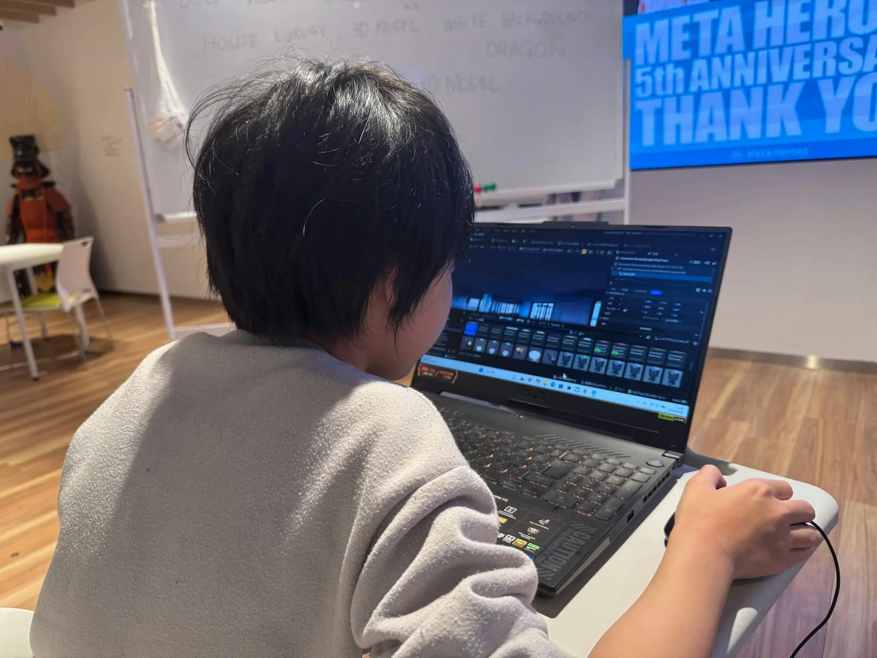 ノートパソコンを操作する人物とスクリーンに映るロゴ