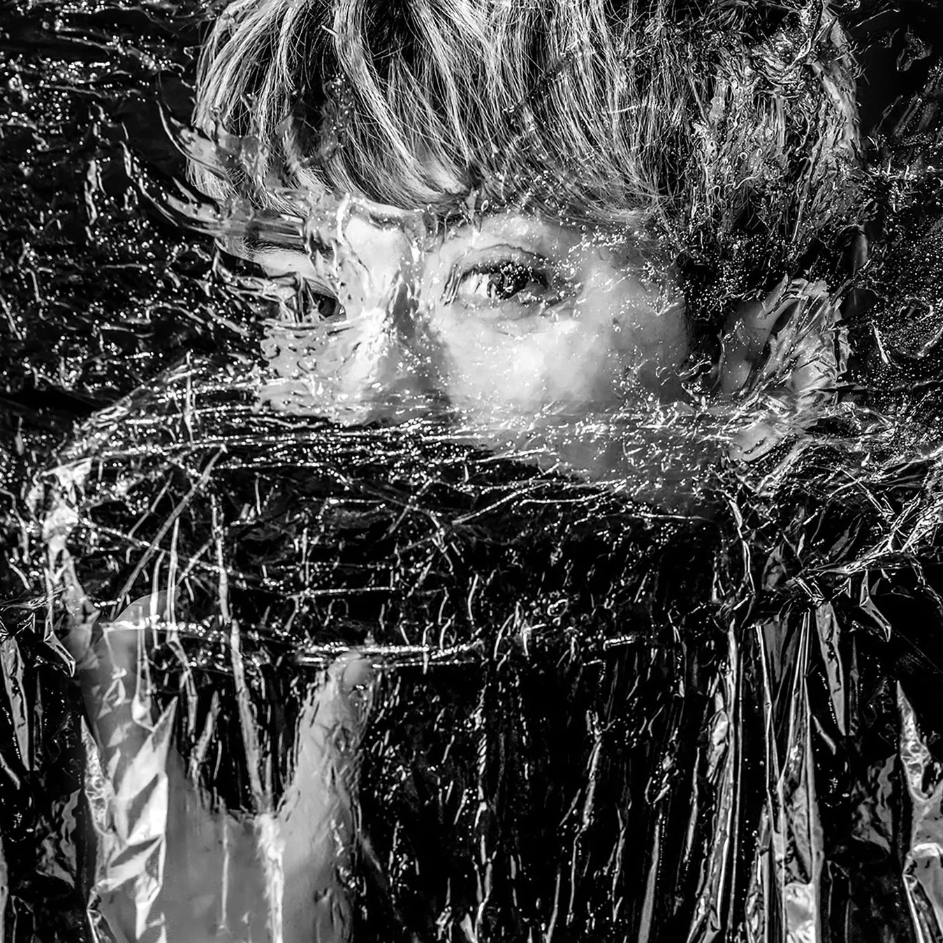 透明な素材を通して顔の一部が歪んで見える人物のポートレート