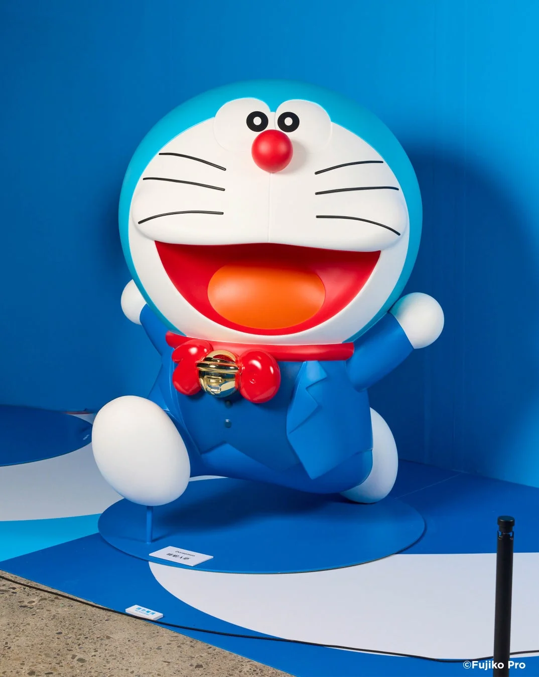 青い背景と床に設置された、走るポーズの大きなドラえもんの像