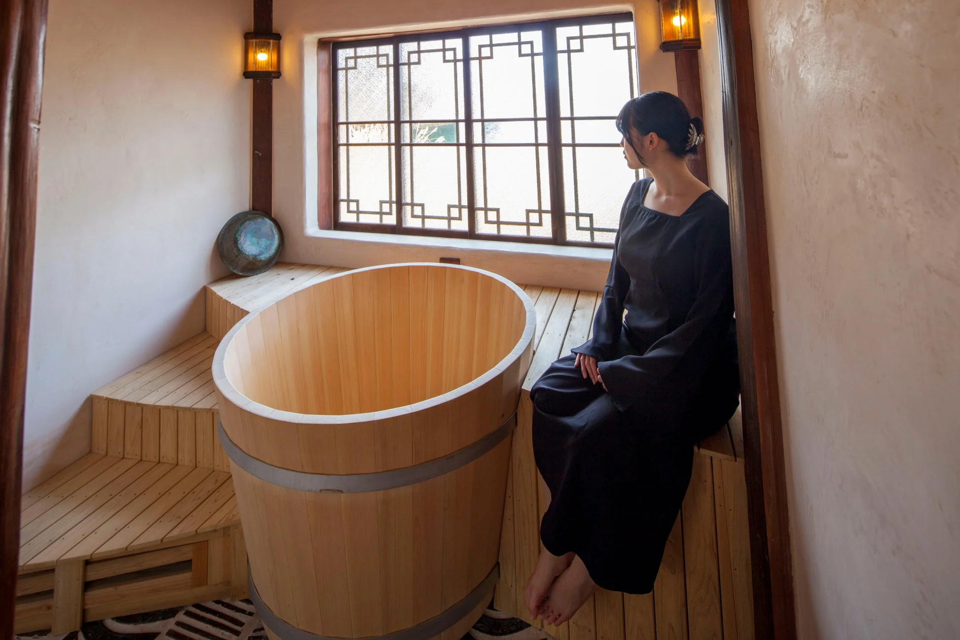 伝統的な桶風呂のそばに座る女性