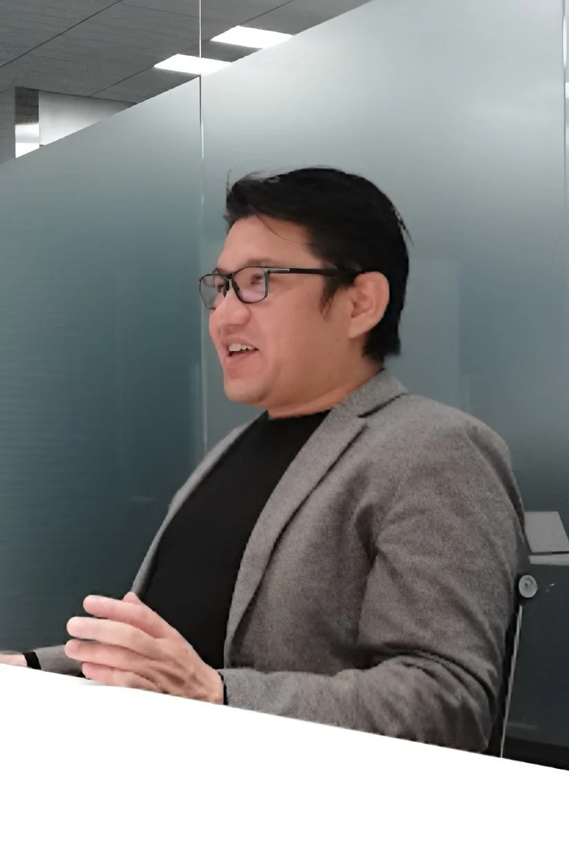 眼鏡をかけた男性が会議で話す様子