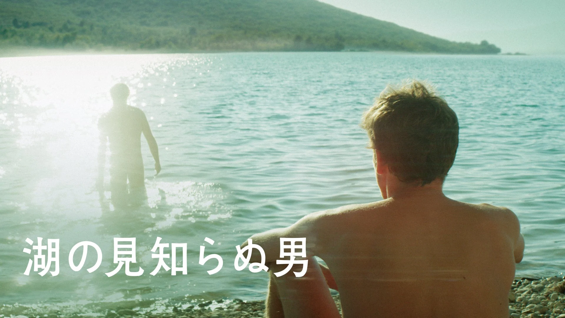 湖畔に座る男性が、水面に立つ見知らぬ男性のシルエットを眺めている