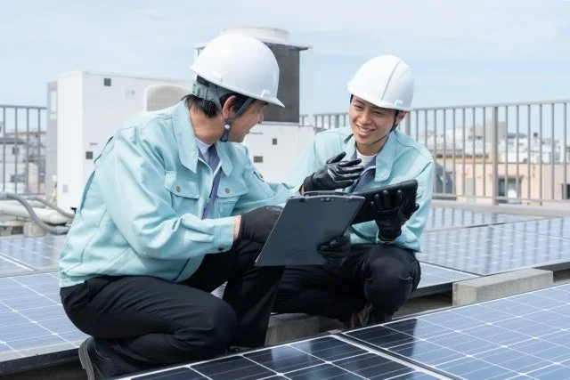 屋上で打ち合わせをする作業員