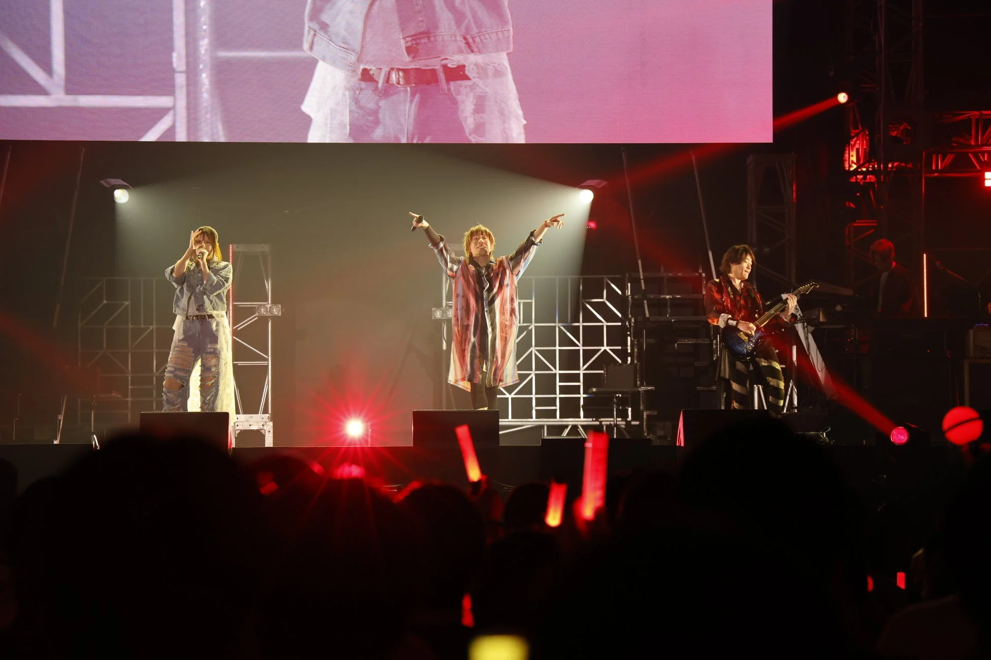 ライブステージでパフォーマンスする3人のアーティスト