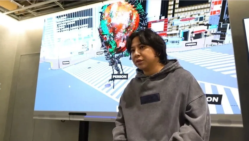 デジタルアートが映し出されたスクリーンの前に立つJACKSON kaki氏