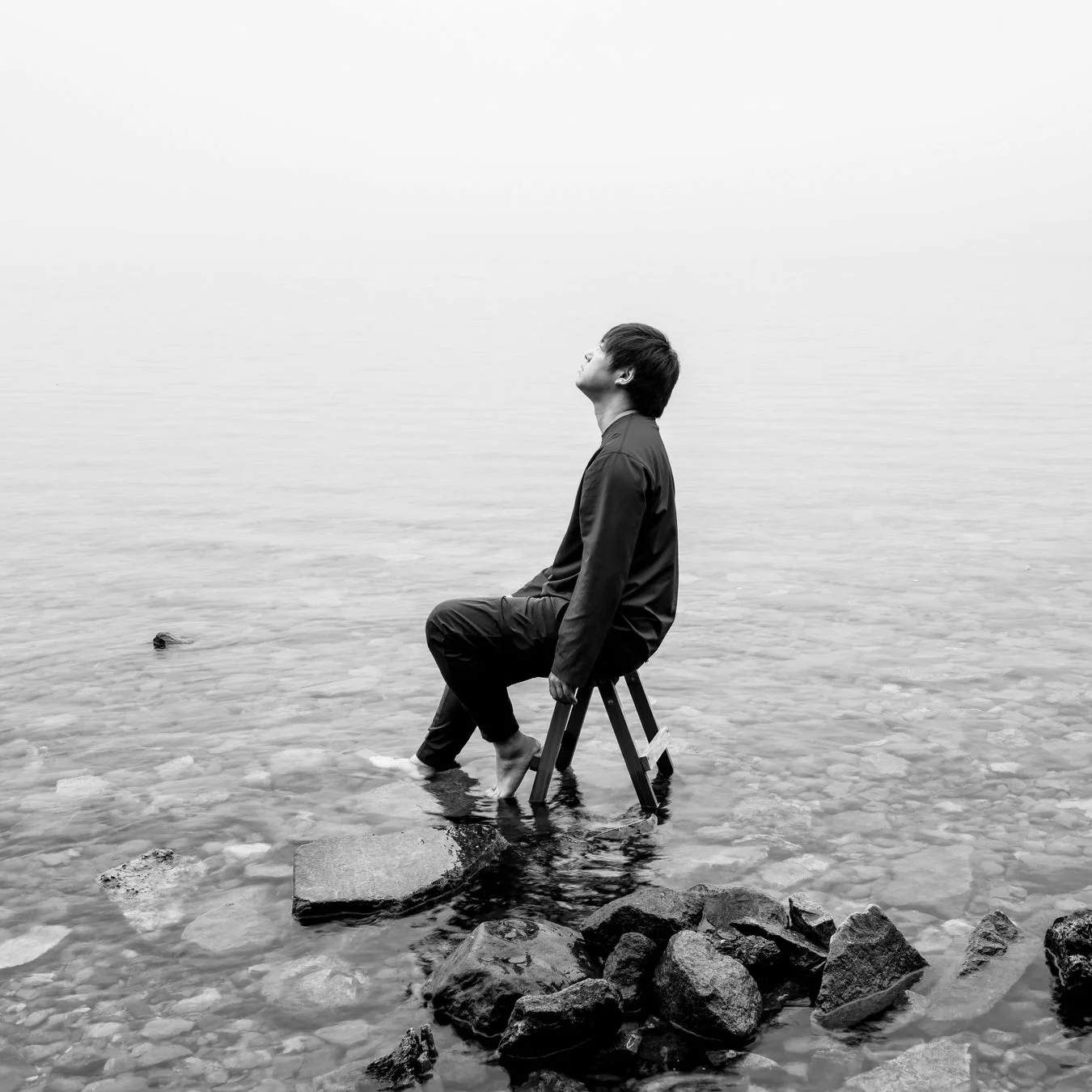 水辺に座る人物のモノクロ写真