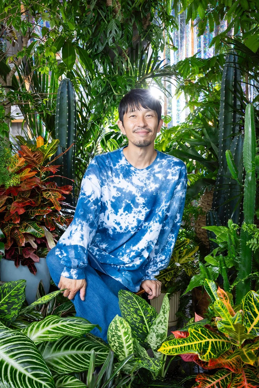 植物に囲まれ笑顔を見せる男性のポートレート