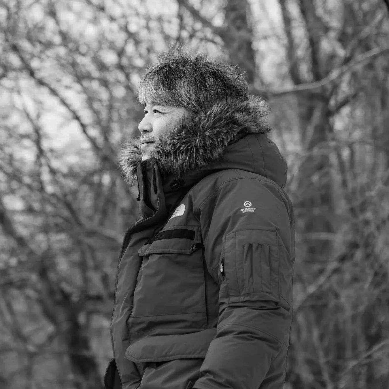 冬の森で遠くを見つめる男性のモノクロ写真